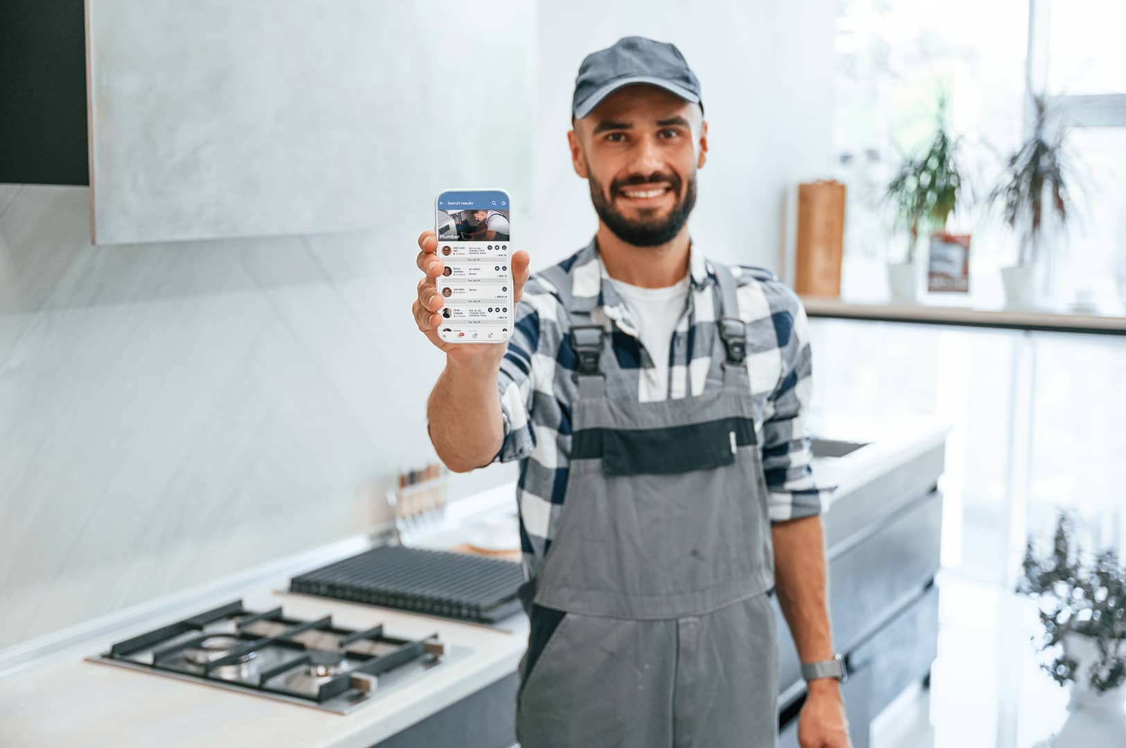 un homme debout dans une cuisine tenant un téléphone portable